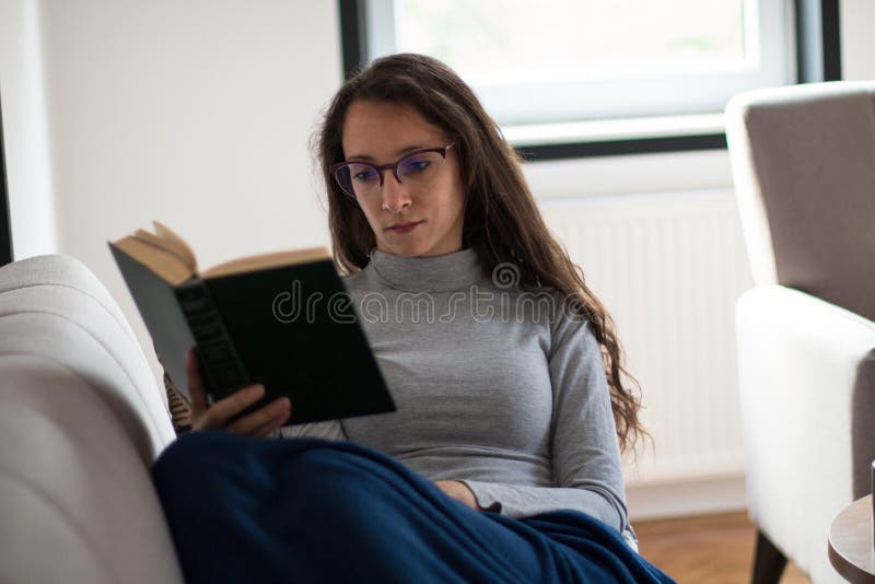 Junge Frau entspannt sich zu Hause mit einem Buch lizenzfreie stockfotografie