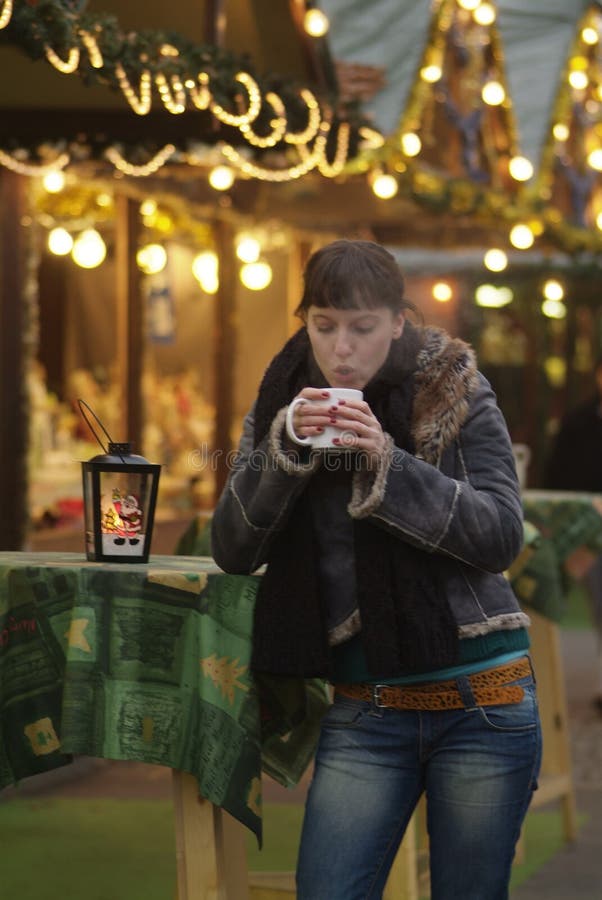 Eine dunkelhaarige Frau Getränke glogg am marktstand.