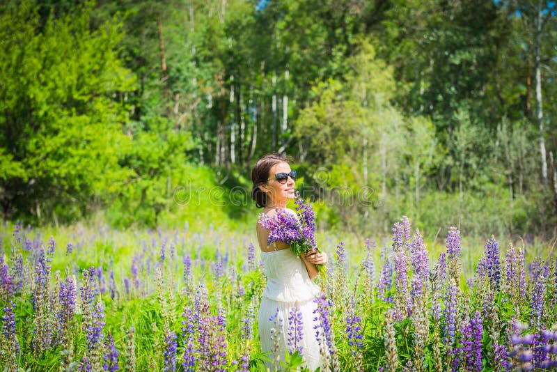 Junge Frau, glücklich, Stellung unter dem Feld von violetten Lupines, lächelnd, purpurrote Blumen Blauer Himmel auf dem Hintergru stockbilder Junge Frau, glücklich, Stellung unter dem Feld von violetten Lupines, lächelnd, purpurrote Blumen Blauer Himmel auf dem Hintergru stockbilder