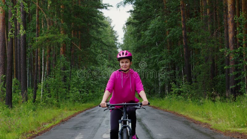 Junge Frau im Helm-Fahrrad auf der Waldstraße