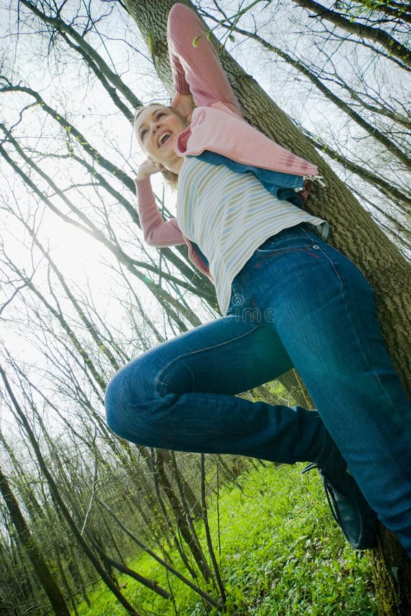 Young woman leaning against a tree and laughing in the forest. Young woman leaning against a tree and laughing in the forest.