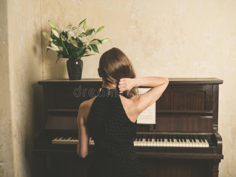 Junge Frau in Kleidung am Klavier lizenzfreies stockbild Junge Frau in Kleidung am Klavier lizenzfreies stockbild