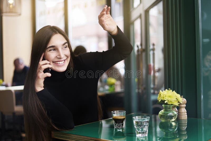 Junge Frau mit dem langen Haar gibt jemand, der Getränkkaffee hallo-fünf, der Rest im Café nahe Fenstertechnik hat lizenzfreies stockfoto