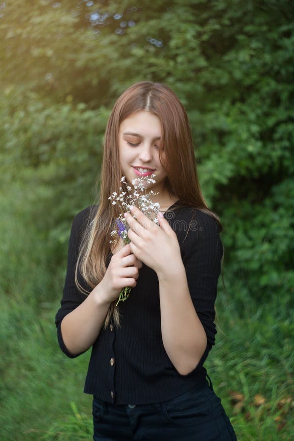 Junge Frau mit einem kleinen Blumenstrauß. Vertikalfoto. stockfotografie