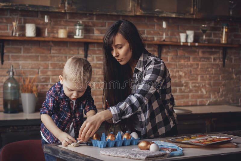 Junge Frau mit ihrem kleinen Sohn, der Ostereier in der Küche malt stockfotografie Junge Frau mit ihrem kleinen Sohn, der Ostereier in der Küche malt stockfotografie