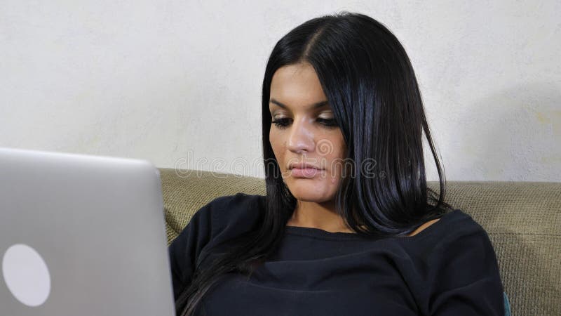 Junge Frau mit Laptop auf der Couch, die an ihrem Startgeschäft arbeitet stockfotos Junge Frau mit Laptop auf der Couch, die an ihrem Startgeschäft arbeitet stockfotos