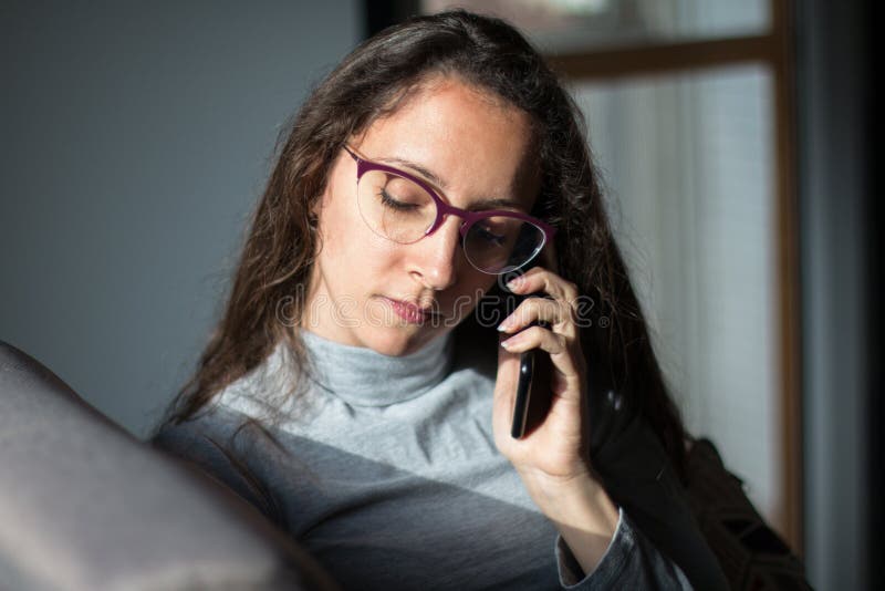 Junge Frau mit unterhaltsamem Telefongespräch zu Hause lizenzfreies stockbild
