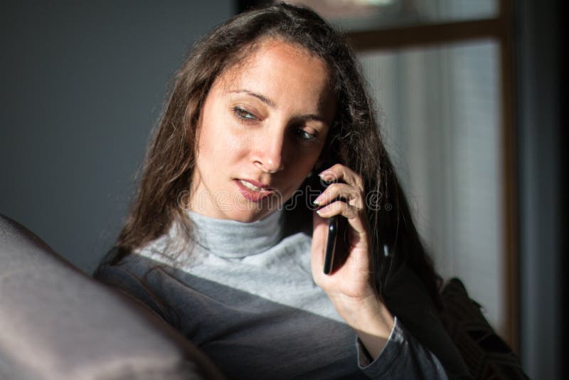 Junge Frau mit unterhaltsamem Telefongespräch zu Hause stockbilder