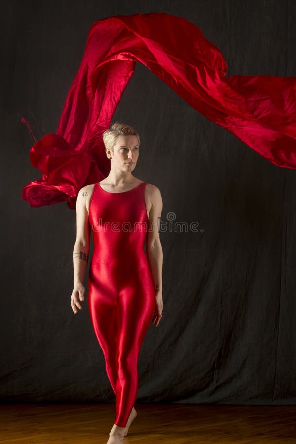 Junge Frau in rotes unitard wirbelndem rotem Gewebe im Studio lizenzfreie stockfotos Junge Frau in rotes unitard wirbelndem rotem Gewebe im Studio lizenzfreie stockfotos