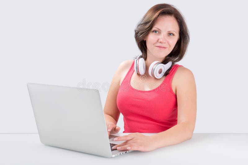 Junge Frau sitzt vor Laptop mit bluetooth headpho