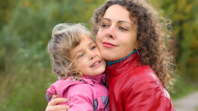 Junge Frau umarmt kleine Tochter im Wind stock footage