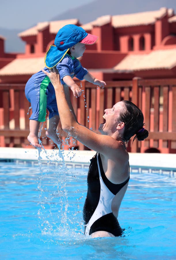 Junge Frau und Tochter, die im Swimmingpool spielt stockbild Junge Frau und Tochter, die im Swimmingpool spielt stockbild