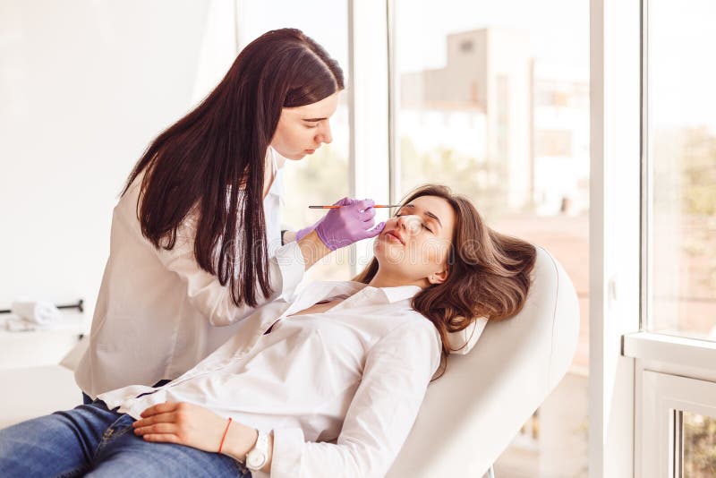 Junge Frauen, die ihre Augenbrauen im Schönheitssalon auszupfen lizenzfreie stockfotografie Junge Frauen, die ihre Augenbrauen im Schönheitssalon auszupfen lizenzfreie stockfotografie