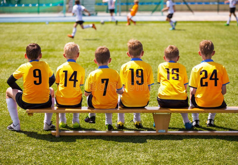 Junge Fußball-Spieler Junger Fußball Team Sitting auf Holzbank lizenzfreies stockfoto Junge Fußball-Spieler Junger Fußball Team Sitting auf Holzbank lizenzfreies stockfoto