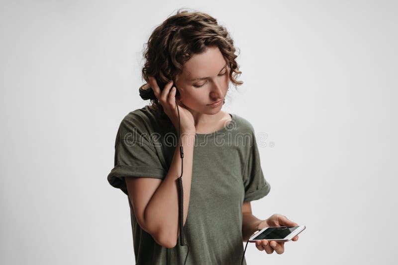 Junge gelockte Frauenfreizeit, halten ihre modernen Stereokopfhörer lizenzfreie stockfotografie Junge gelockte Frauenfreizeit, halten ihre modernen Stereokopfhörer lizenzfreie stockfotografie