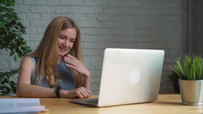 Junge Geschäftsfrau, die im Büro mit dem Laptop hat Videochat sitzt Berufsfrau, die den Computer spricht über verwendet