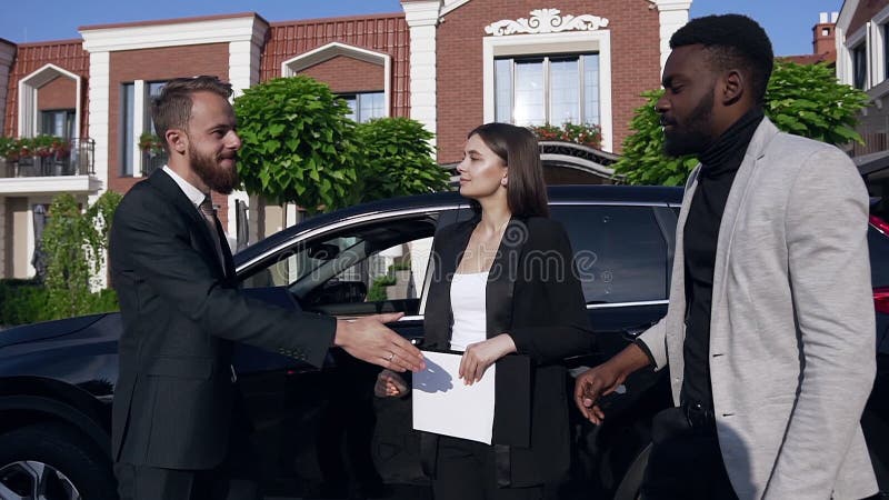 Junge Geschäftsfrau mit afro-amerikanischem und kaukasischem Mann schüttelt die Hände und dankt für erfolgreiche Teamarbeit