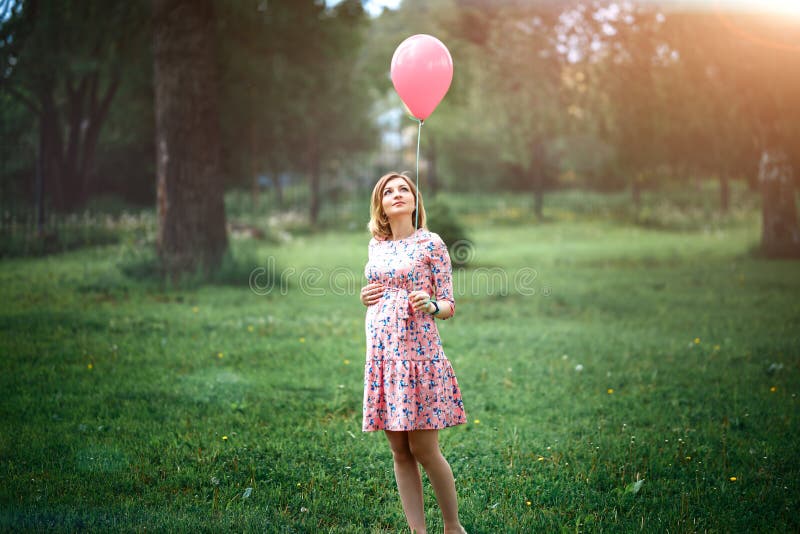 Junge glückliche schwangere Frau mit rosa Ballon draußen lizenzfreie stockfotografie Junge glückliche schwangere Frau mit rosa Ballon draußen lizenzfreie stockfotografie