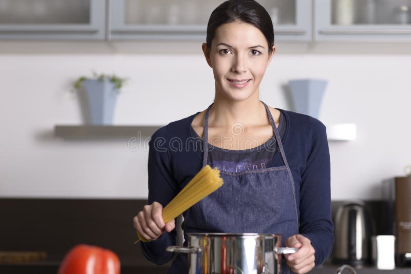 Junge Hausfrau, die gesunden italienischen Teigwaren zubereitet stockbild Junge Hausfrau, die gesunden italienischen Teigwaren zubereitet stockbild