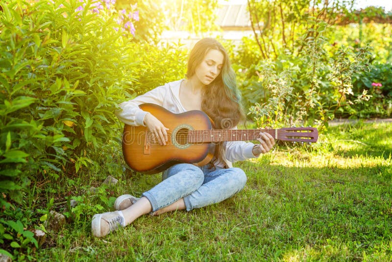 Junge Hippie-Frau, die im Gras sitzt und Gitarre auf Park- oder Gartenhintergrund spielt Jugendlich M?dchen, das lernt, Lied zu s lizenzfreie stockbilder Junge Hippie-Frau, die im Gras sitzt und Gitarre auf Park- oder Gartenhintergrund spielt Jugendlich M?dchen, das lernt, Lied zu s lizenzfreie stockbilder