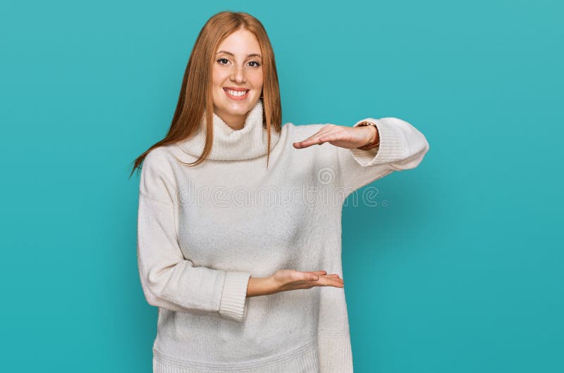 Junge irische Frau, die einen lockeren Winterpulli mit Händen trägt, die ein großes und großes Zeichen-Symbol zeigen stockfoto