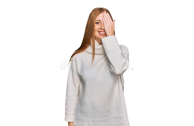 Junge irische Frau, die einen lockeren Winterpullover mit einem Auge trägt, mit einem handfesten Lächeln im Gesicht und überrasche lizenzfreie stockfotografie