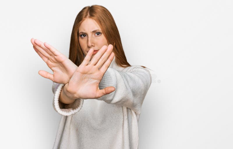 Junge irische Frau, die einen lockeren Winterschwitzausdruck trug, der Arme und Handflächen überquerte und dabei negative Zeichen stockfoto