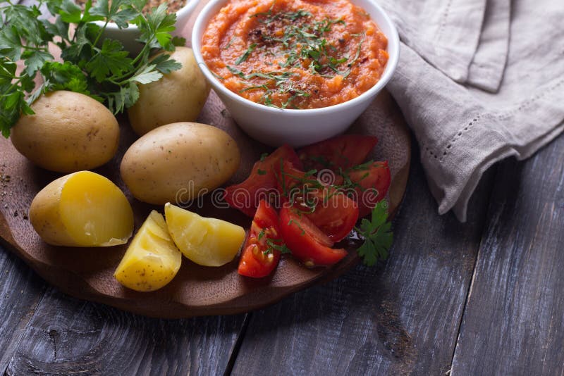 Junge Kartoffeln gekocht in einer Schale mit Zucchinikaviar, Gewürzen, frischen Tomaten und Petersilie lizenzfreies stockbild Junge Kartoffeln gekocht in einer Schale mit Zucchinikaviar, Gewürzen, frischen Tomaten und Petersilie lizenzfreies stockbild