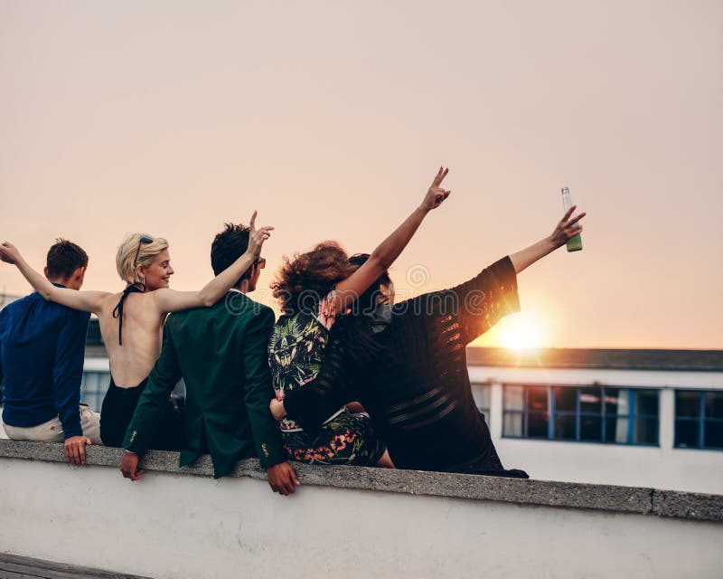 Junge Leute, die auf Terrasse mit Getränken partying sind lizenzfreies stockfoto Junge Leute, die auf Terrasse mit Getränken partying sind lizenzfreies stockfoto
