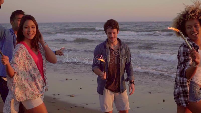 Junge Leute mit Brunnen-Kerzen auf dem Strand