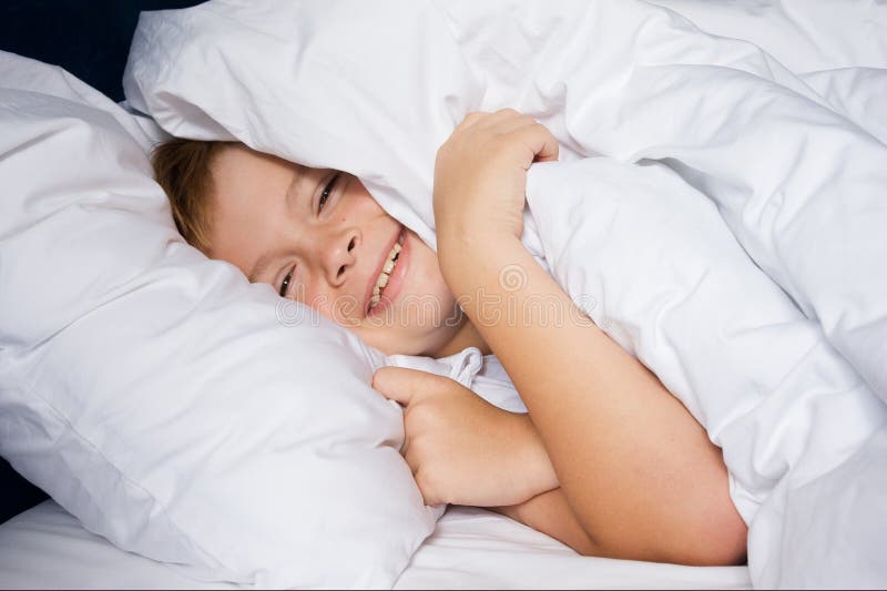 Junge Junge liegt im Schlafzimmer und lächelt stockfotografie Junge Junge liegt im Schlafzimmer und lächelt stockfotografie