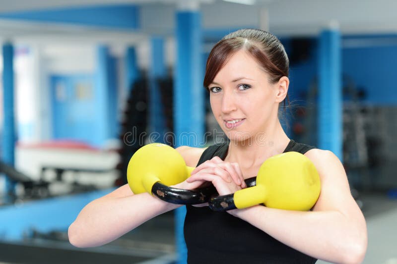 Junge lächelnde Frau beim Anheben der Kesselglocke stockbild Junge lächelnde Frau beim Anheben der Kesselglocke stockbild