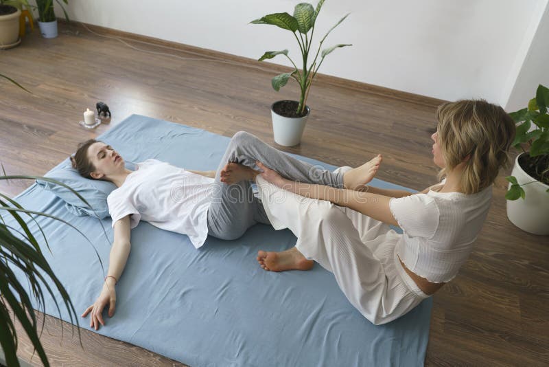 Junge Masseurin Massiert Auf Dem Boden Ein Mädchen Das Sich Die Füße Massiert Stockbild Bild