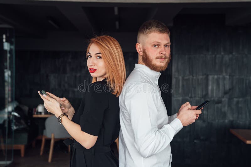 Junge Menschen stehen sich mit einem Smartphone in der Hand mit dem Rücken stockbild Junge Menschen stehen sich mit einem Smartphone in der Hand mit dem Rücken stockbild