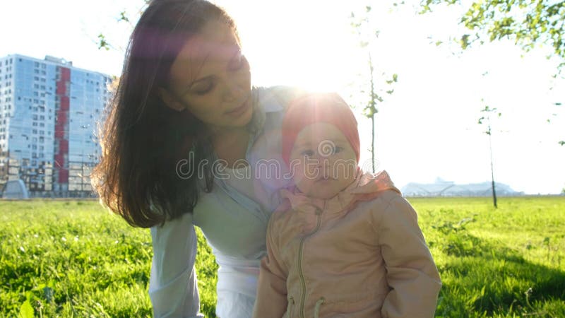 Junge Mutter, die ihr Kind zum Abstand zeigt und etwas erklärt Europäische Familie, die im Park auf sitzt stockbild Junge Mutter, die ihr Kind zum Abstand zeigt und etwas erklärt Europäische Familie, die im Park auf sitzt stockbild