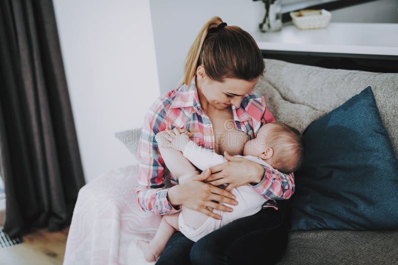 Junge Mutter, die zuhause kleines Baby stillt lizenzfreies stockfoto Junge Mutter, die zuhause kleines Baby stillt lizenzfreies stockfoto