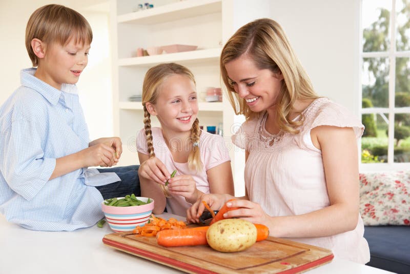 Junge Mutter mit den Kindern, die Gemüse abziehen