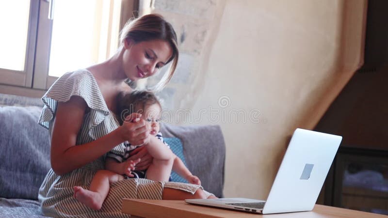 Junge Mutter mit einem Kind, das mit Computer arbeitet