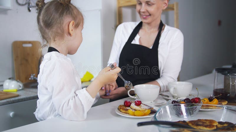 Junge Mutter mit ihrem Kind, das zusammen selbst gemachte Pfannkuchen kocht stockfotografie Junge Mutter mit ihrem Kind, das zusammen selbst gemachte Pfannkuchen kocht stockfotografie