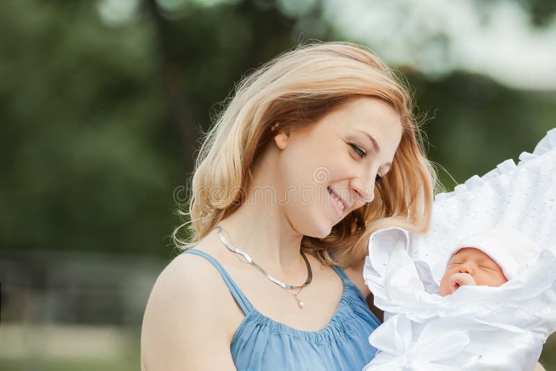 Junge Mutter mit neugeborenem Kind im unscharfen Hintergrund der Natur stockfotografie