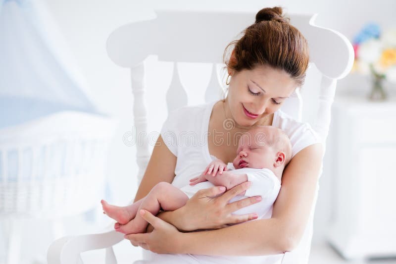 Junge Mutter und neugeborenes Baby im weißen Schlafzimmer lizenzfreie stockfotos Junge Mutter und neugeborenes Baby im weißen Schlafzimmer lizenzfreie stockfotos