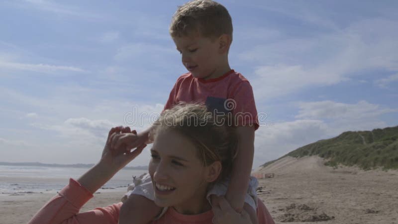 Junge Mutter und Sohn, die entlang den Strand geht