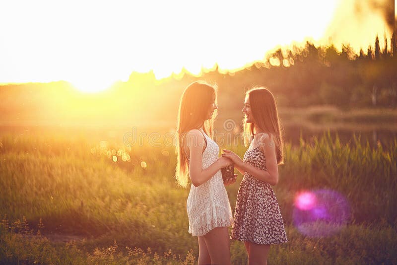 Junge Mädchen, die in Sonnenstrahlen auf Gras stehen und Händen halten stockfotos
