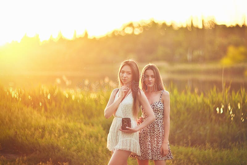 Junge Mädchen, die in Sonnenstrahlen auf Gras stehen und reden lizenzfreies stockfoto