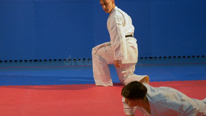 Junge Männer, die Kimono mit Selbstverteidigungs-Karatetechniken des schwarzen Gürtels übenden am Dojo tragen