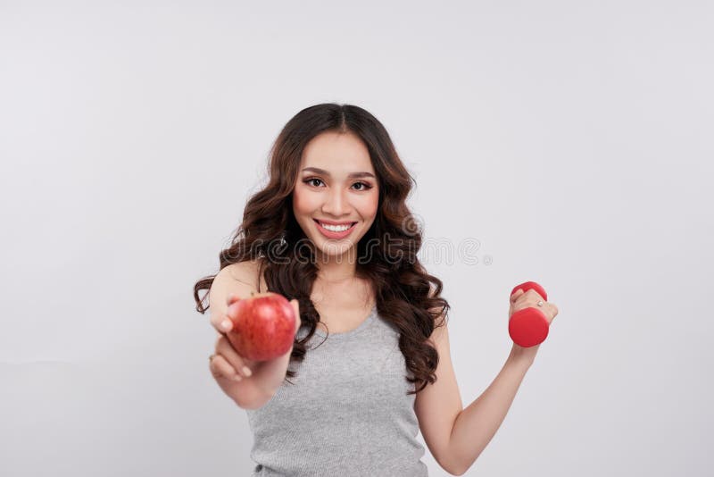 Junge nette asiatische Frau, die Dummköpfe und roten Apfel hält lizenzfreie stockfotos Junge nette asiatische Frau, die Dummköpfe und roten Apfel hält lizenzfreie stockfotos