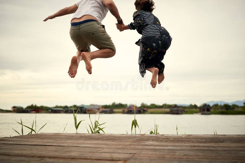 Junge Paare in der Liebe, die auf das Ufer des Sees springt