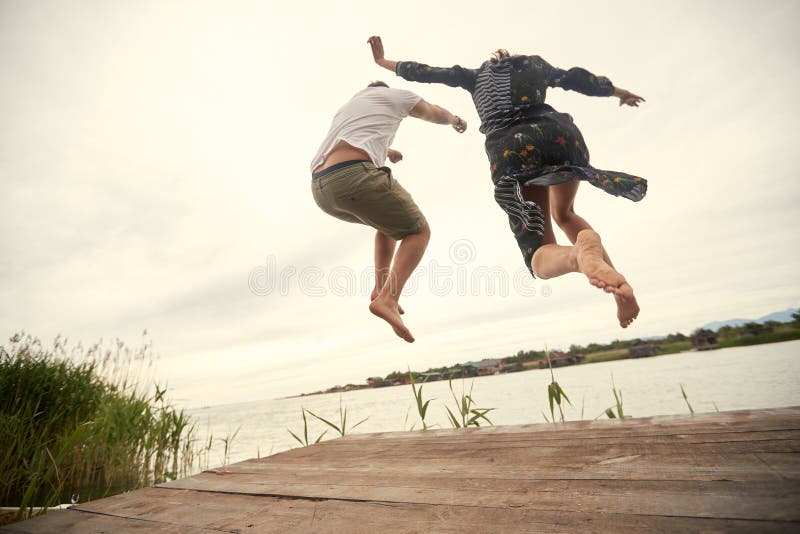 Junge Paare, die auf das Ufer des Sees springen.