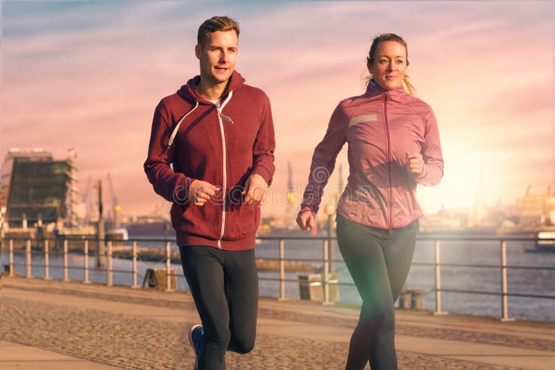 Junge Paare, die auf einer Seeseitepromenade laufen stockbilder Junge Paare, die auf einer Seeseitepromenade laufen stockbilder
