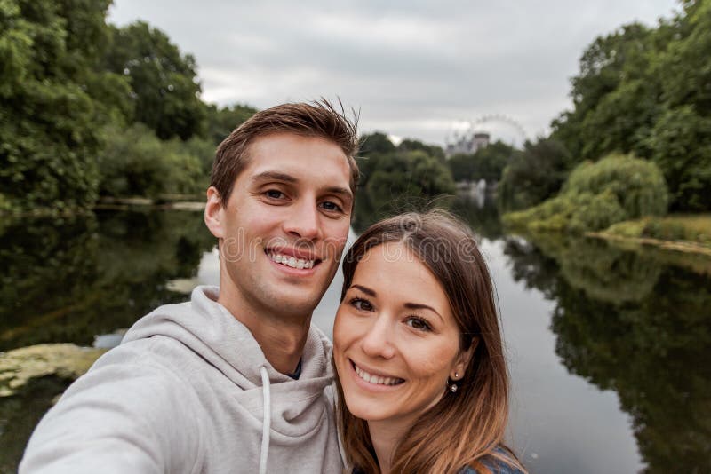 Junge Paare, die ein selfie am Park in London nehmen stockfotografie Junge Paare, die ein selfie am Park in London nehmen stockfotografie